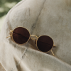 Oliver Peoples sunglasses folded on a blanket.